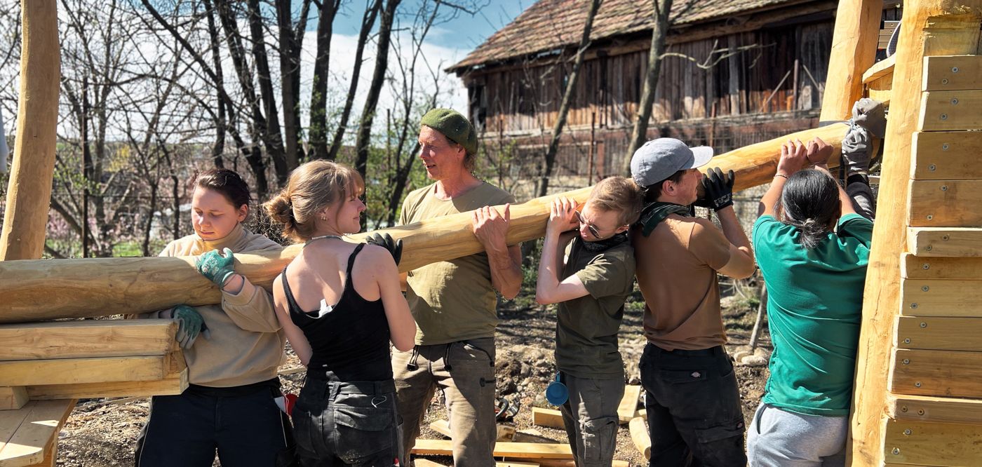 Gruppe trägt gemeinsam einen Holzstamm