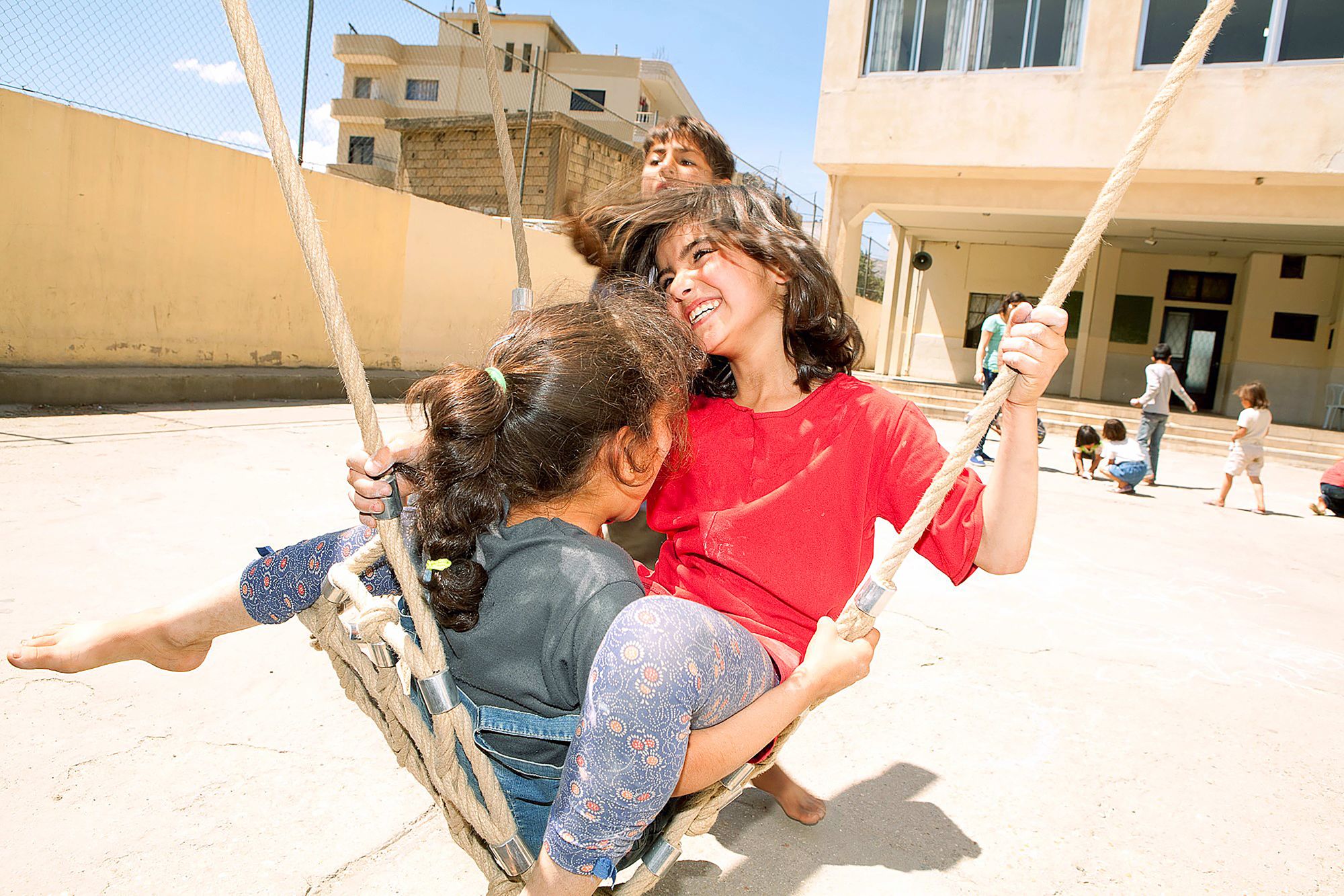 Kinder lachen gemeinsam in einer Nestschaukel im Libanon