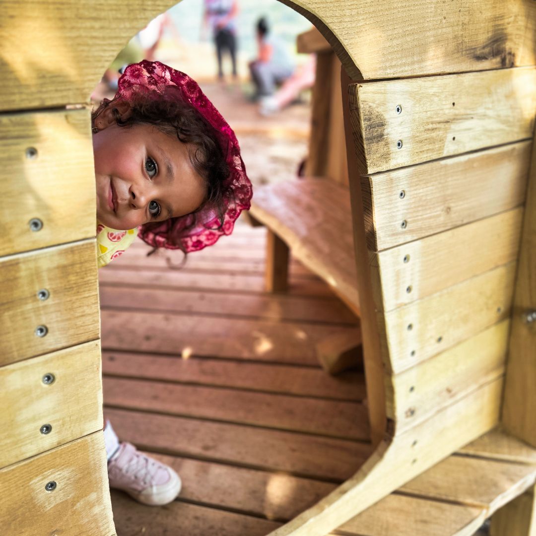 Kleines Mädchen schaut aus einem Holzspielhaus
